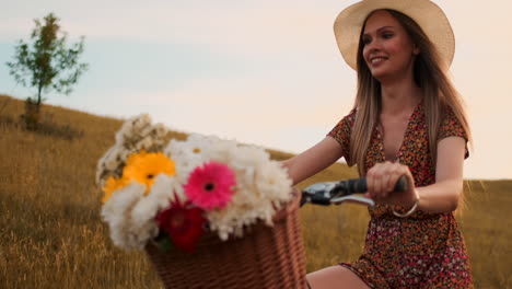Ein-Mädchen-In-Einem-Kleid-Fährt-Fahrrad-Mit-Blumen-In-Einem-Korb-Und-Genießt-Lachend-Die-Freiheit-Und-Die-Sommerluft.-Zeitlupe.